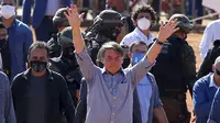 Presiden Brasil Jair Bolsonaro (tengah) melambaian tangan kepada pendukungnya saat peresmian rumah sakit lapangan di Aguas Lindas, Goiais, Brasil, 5 Juni 2020. Hingga 6 Juli 2020, otoritas Brasil melaporkan 1,6 juta orang dinyatakan positif dan 65 ribu di antaranya meninggal dunia. (Sergio LIMA/AFP)