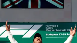 Pembalap Mercedes, Lewis Hamilton berselebrasi setelah berhasil menjuarai GP Hungaria di Sirkuit Hungaroring, Mogyorod, (29/7). Hamilton berhasil menjaga selisih 24 poin dari pesaing terdekatnya, pebalap Ferrari, Sebastian Vettel. (AP Photo/Laszlo Balogh)
