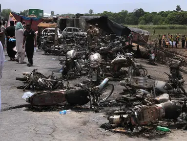 Sejumlah bangkai kendaraan yang hangus terbakar akibat ledakan truk tangki minyak yang terbalik dan meledak di jalan raya dekat Bahawalpur, Pakistan (25/6). Dikabarkan, sedikitnya 123 orang tewas dan 100 lainnya mengalami luka-luka. (AP Photo / Iram Asim)