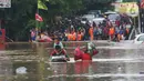 Warga melintasi banjir  yang merendam jalan Raya KH Hasyim Ashari, Ciledug ,Tangerang, Rabu (1/1/2020). Banjir setinggi dada orang dewasa membuat jalur penghubung Tangerang ke Jakarta tersebut terputus tidak dapat dilintasi. (Liputan6.com/Angga Yuniar)