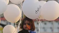 Pria dan anaknya memegang balon saat upacara untuk memperingati peristiwa ledakan pelabuhan 4 Agustus di Beirut, Lebanon, 4 Oktober 2020. Dua ledakan yang mengguncang Pelabuhan Beirut menghancurkan sebagian kota dan menewaskan sekitar 190 orang serta melukai 6.000 lainnya. (Xinhua/Bilal Jawich)