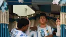 Fans Argentina Shib Shankar Patra menyesuaikan patung Lionel Messi yang dipasang di samping kedai tehnya yang dicat dengan warna tim, di Ichhapur sekitar 35 km sebelah utara Kolkata pada 12 Desember 2022. Argentina berhasil lolos ke babak semifinal Piala Dunia 2022 Qatar yang akan melawan Kroasia. (AFP/Dibyangshu Sarkar)