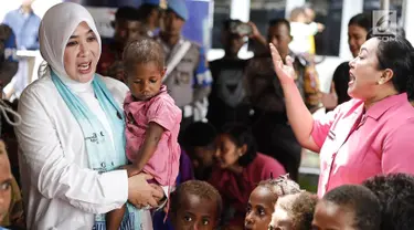 Ketum Bhayangkari, Tri Suswati Tito Karnavian menggendong anak korban bencana banjir Sentani di Kabupaten Jayapura, Jumat (22/3). Tri Tito dan Polwan melakukan trauma healing dengan mengajak bernyanyi dan bermain. (Liputan6.com/Pool/Humas Mabes Polri)