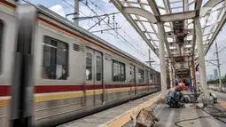 Kereta melintas saat pekerja menyelesaikan pembangunan Stasiun Matraman, Jakarta Timur, Kamis (23/12/2021).  Stasiun Matraman yang berada antara Stasiun Manggarai dan Jatinegara ini diharapkan dapat memecah kepadatan penumpang di kedua stasiun tersebut. (merdeka.com/Iqbal S. Nugroho)