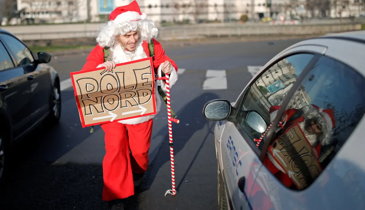 Remi Le Calvez, menghampiri sebuah mobil saat ia mencari tumpangan dengan mengenakan kostum Santa Claus di Paris, Prancis, Selasa (6/12). Remi membagi pengalaman dari perjalanannya kepada orang-orang lewat blog dan Facebooknya. (Reuters/Benoit Tessier)