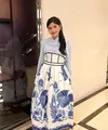 Erina Gudono tampil mengenakan rok high waist warna putih dengan aksen batik ikan floral waena biru. Dipadukan dengan kemeja lengan panjang baby blue dan bros di bagian kerah. Ia pun memadukan dengan sandal Hermes warna coklat. [@erinagudono]