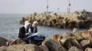 Lokakarya ini memberi ruang untuk memproses trauma melalui warna dan kreativitas. Tampak dalam foto, para perempuan muda berinteraksi sambil melukis di pelabuhan Kota Gaza pada Kamis 12 Februari 2026. (Omar AL-QATTAA/AFP)