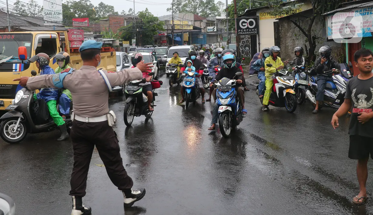 Petugas kepolisian mengatur lalu lintas saat melakukan penutupan jalan KH Hasyim Ashari, Kota Tangerang, Banten, Sabtu (16/7/2022). Akibat banjir yang merendam kawasan tersebut membuat petugas harus menutup jalur dan memutarbalikan para pengendara yang melintas. (Liputan6.com/Angga Yuniar)