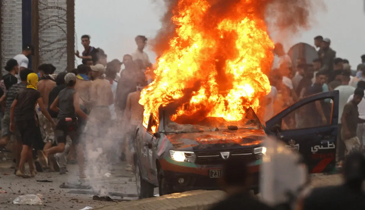 Para Imigran membakar mobil di lokasi bentrokan dekat Fnideq, di perbatasan Maroko-Spanyol, Jumat, 31 Juli 2026. (AFP/  Abdel Majid Bziouat)