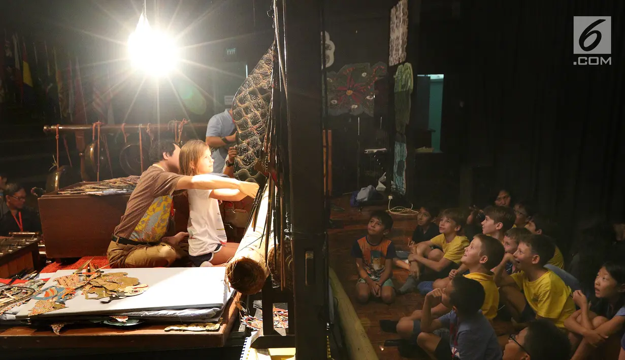Dalang Ki Purbo Asmoro mengajar siswa belajar mendalang yang disaksikan sejumlah siswa pada pagelaran wayang kulit di Jakarta Intercultural School (JIS) Elementary, Jakarta, Kamis (2/11). (Liputan6.com/Fery Pradolo)