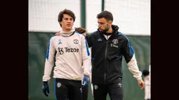 Gelandang Manchester United, Bruno Fernandes (kanan) berbicara dengan rekannya, Facundo Pellistri saat sesi latihan di pusat latihan Carrington, Manchester, Senin (17/4/2023) sebagai persiapan jelang laga leg kedua Liga Europa 2022/2023 menghadapi Sevilla. (twitter.com/ManUtd)