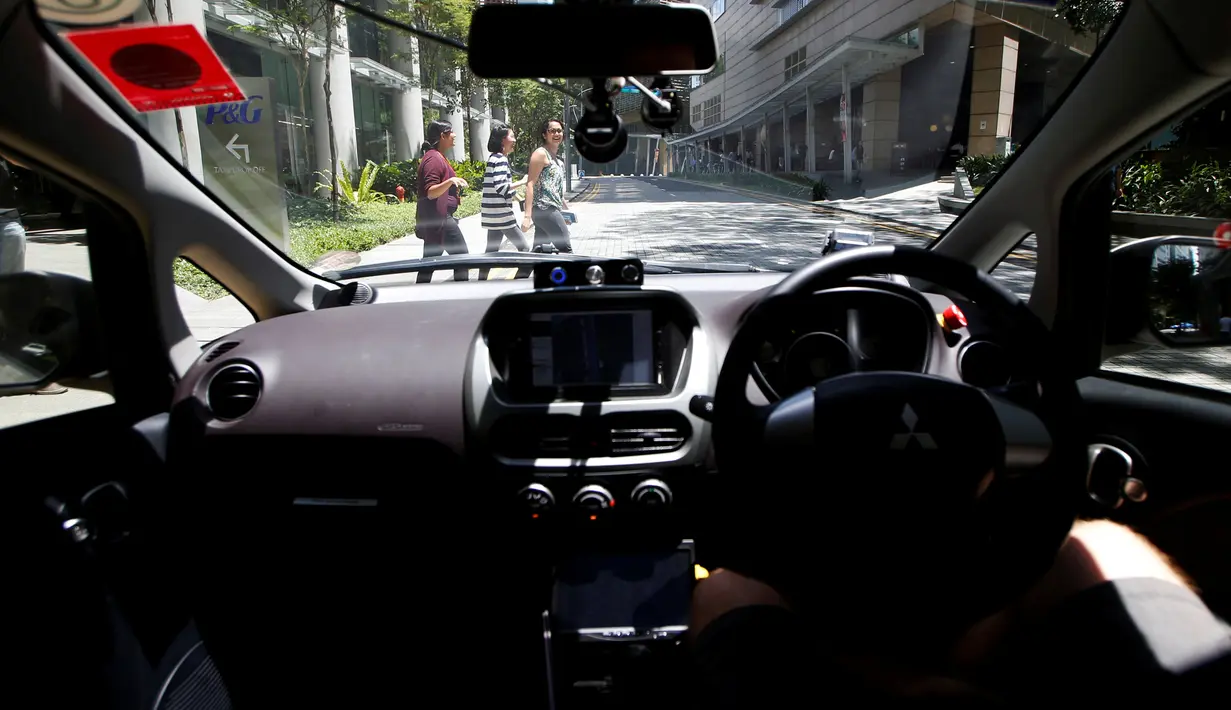 Pejalan kaki menyeberang di depan taksi tanpa sopir dalam uji coba di jalan raya Singapura, Kamis (25/8). Untuk bisa mendapatkan kesempatan naik taksi otonom calon penumpang harus memesan melalui aplikasi melalui operator nuTonomy. (REUTERS/Edgar Su)
