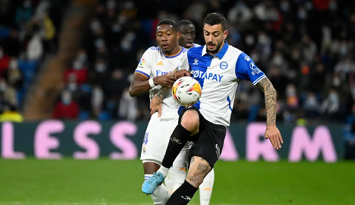 Pemain depan Deportivo Alaves Joselu (kanan) berebut bola dengan bek Real Madrid David Alaba pada pekan ke-25 La Liga Spanyol di Santiago Bernabeu, Minggu (20/2/2022) dinihari WIB. Real Madrid menang meyakinkan dengan skor 3-0. (OSCAR DEL POZO / AFP)