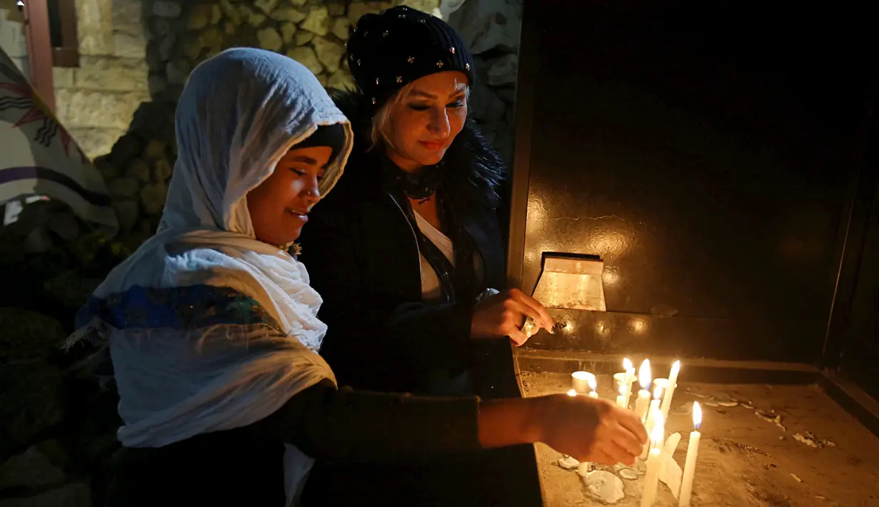 Umat Kristiani Irak menyalakan lilin setelah Misa Malam Natal di Gereja St. Joseph di Baghdad, Irak, Minggu (24/12). (AP Photo / Karim Kadim)