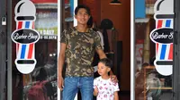 Pemain Arema, Ahmad Alfarizi, dengan putranya, Diego, di depan barbershop-nya. (Bola.com/Iwan Setiawan)