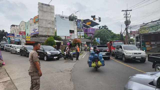 Anggota Satpol PP Kota Depok berjaga dan mengatur lalu lintas di simpang tugu batu Sawangan, Depok.