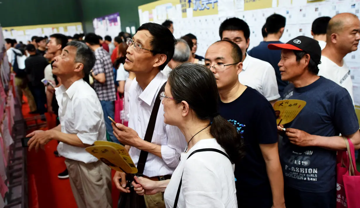 Sejumlah pria dan wanita melihat daftar pria lajang saat acara perjodohan di Hangzhou, Provinsi Zhejiang, China (14/5). (AFP Photo/Str/China Out)