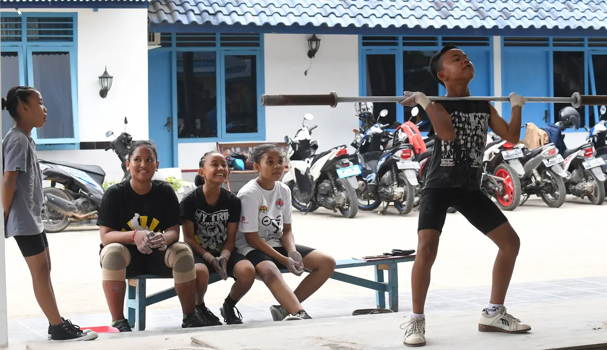Seorang anak berusaha mengangkat besi disaksikan rekan-rekanya saat berlatih di Padepokan Gajah, sebuah akademi swasta di Pringsewu, Kabupaten Lampung, Sumatera Selatan (7/11). (AFP Photo/GOH Chai Hin)