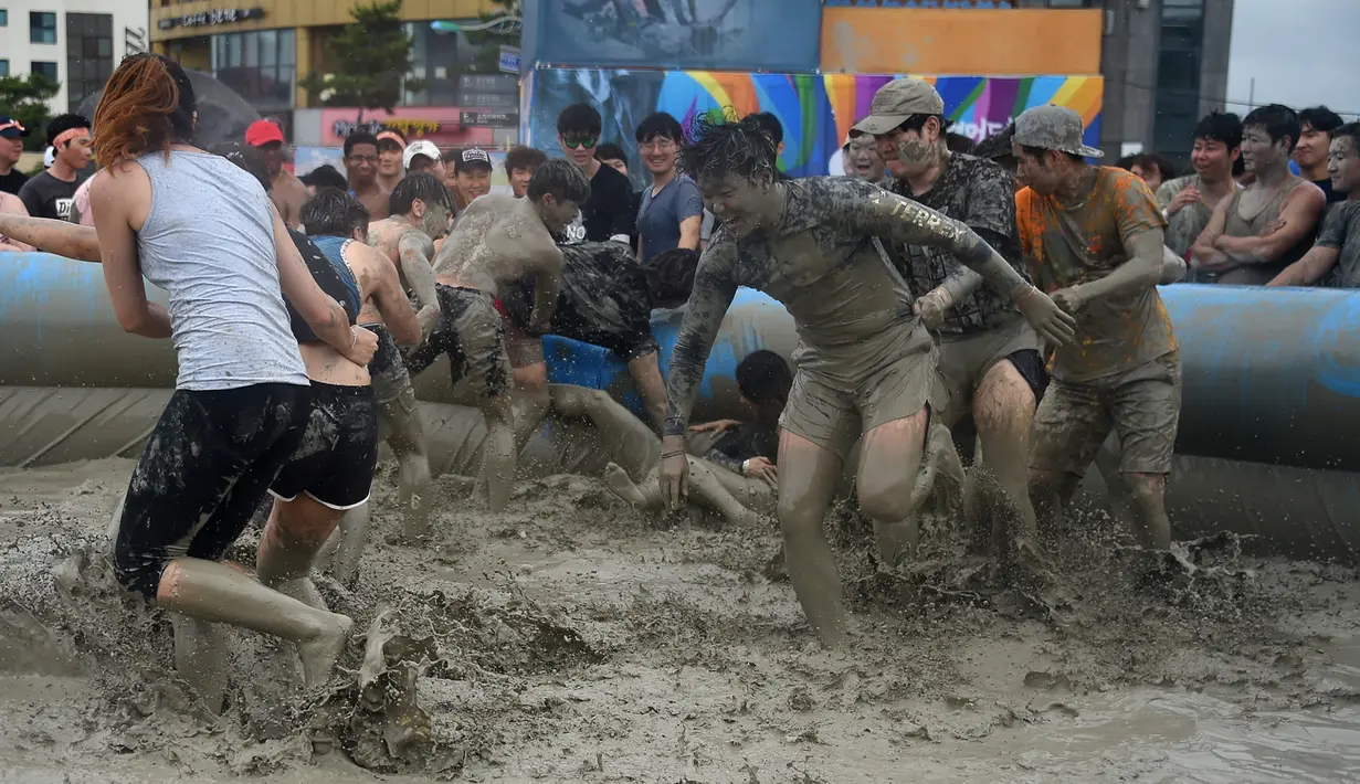 Wisatawan bermain di kolam lumpur selama Boryeong Mud Festival atau Festival Lumpur Boryeong di pantai Daecheon, Korea Selatan, Sabtu (20/7/2019). Festival ini dikenal sebagai festival paling populer di Korea Selatan dan berhasil mengundang ribuan turis dari seluruh penjuru dunia. (Minji SUH/AFP)