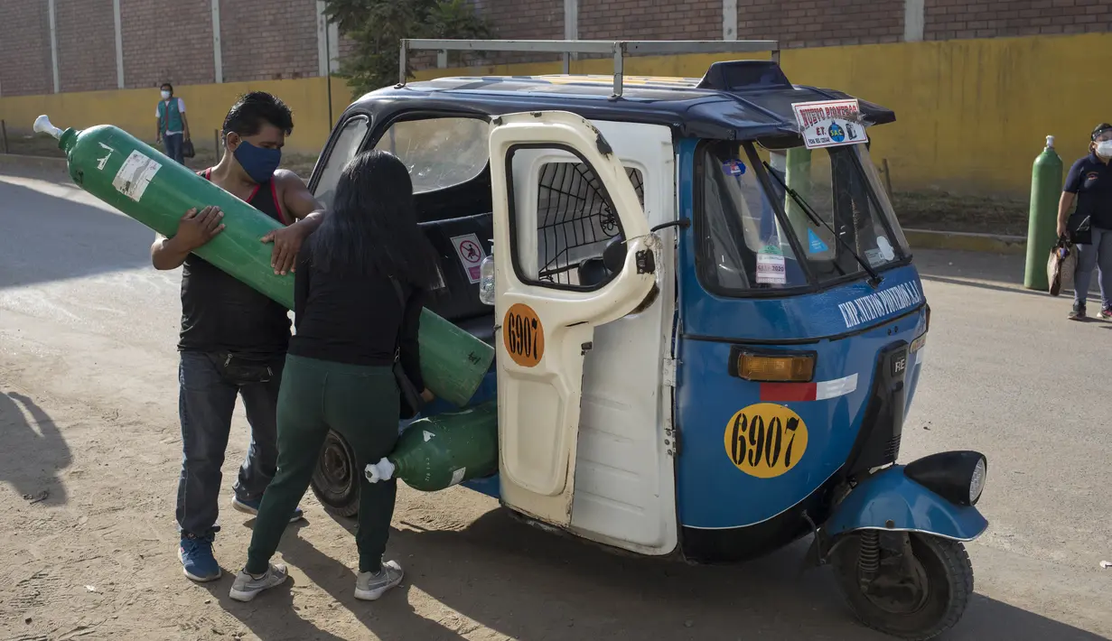 Sepasang suami istri memuat tangki oksigen yang baru diisi ke dalam ojek untuk orang tercinta yang terinfeksi COVID-19 di Villa El Salvador, Lima, Peru, Selasa (6/4/2021). Warga Peru terus berjuang mendapatkan oksigen medis untuk merawat pasien COVID-19. (AP Photo/Rodrigo Abd)