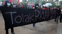 Massa membentangkan spanduk saat melakukan demontrasi di depan Gedung MPR/DPR, Jakarta, Senin (12/2). Mereka menolak KUHP dengan alasan KUHP tidak berpihak pada kelompok marjinal utamanya, Perempuan, Anak, ODHA, Minoritas, LGBT. (Liputan6.com/Johan Tallo)