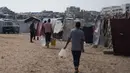 Warga hanya mendapatkan 6 hingga 7 liter air per hari, jauh di bawah standar kemanusiaan. Tampak dalam foto, para pengungsi Palestina membawa jerigen berisi air melalui kamp tenda di Khan Younis, Jalur Gaza Selatan, Kamis 30 April 2026. (AP Photo/Abdel Kareem Hana)