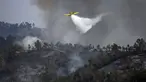 Sebuah pesawat pemadam kebakaran menjatuhkan air di atas api di Odeceixe, selatan Portugal, Selasa (8/8/2023). Ratusan petugas pemadam kebakaran berusaha memadamkan api yang berkobar di Portugal selatan yang telah menghanguskan ribuan hektare lahan dan menyebabkan sekitar 1.400 orang dievakuasi untuk berjaga-jaga. (Patricia DE MELO MOREIRA/AFP)