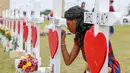 Siswi SMA Santa Fe, Jai Gillard menulis pesan pada salib di depan sekolah mereka di Texas, Amerika Serikat, Senin (21/5). Penembakan di sekolah Santa Fe beberapa waktu lalu menewaskan 10 orang. (Steve Gonzales/Houston Chronicle via AP)