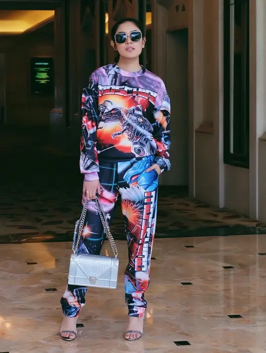 Masih dengan piyamanya yang kali ini bermotif robot. Nindy pun menambahkan aksesoris dengan cincin dan kaca mata hitamnya yang keren banget.  Tak lupa tas dan heels yang warnanya serupa. (Instagram/nindyparasadyharsono)