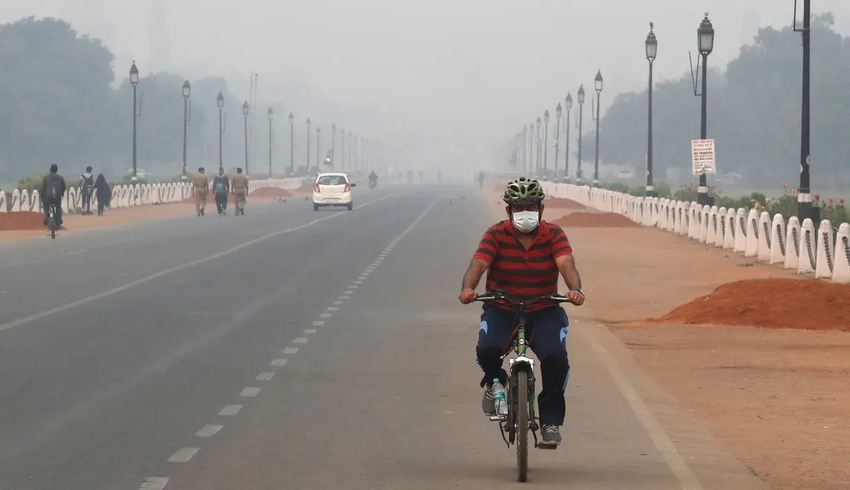 Seorang pria India mengenakan masker sambil mengendarai sepeda di tengah kabut tipis di New Delhi, India (28/10/2019). Menurut pemerintah New Delhi kualitas udara buruk setelah festival Hindu Diwali tahun ini masih lebih baik daripada tiga tahun terakhir. (AP Photo/Manish Swarup)