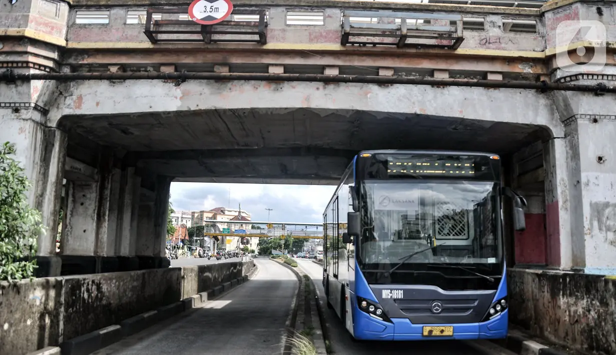Bus Transjakarta melintas di bawah Jembatan Kereta Matraman, Jakarta Timur, Senin (10/1/2022). Penetapan Jembatan Kereta Matraman sebagai cagar budaya dilakukan untuk pelestarian sekaligus memperkenalkan masyarakat tentang sejarah di Ibu Kota. (merdeka.com/Iqbal S. Nugroho)