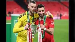 Pemain Manchester United, David De Gea (kiri) dan Bruno Fernandes berpose bersama trofi Carabao Cup 2023 setelah mengalahkan Newcastle United di Wembley Stadium, Minggu (26/2/2023) waktu setempat. (AFP/Glyn Kirk)