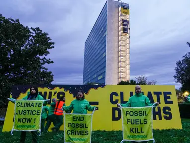 Aktivis organisasi lingkungan Greenpeace membuka spanduk di samping gedung kantor pusat ENI—perusahaan minyak dan gas Italia—di Roma, Italia, Selasa, 5 Desember 2023. (AP Photo/Andrew Medichini)