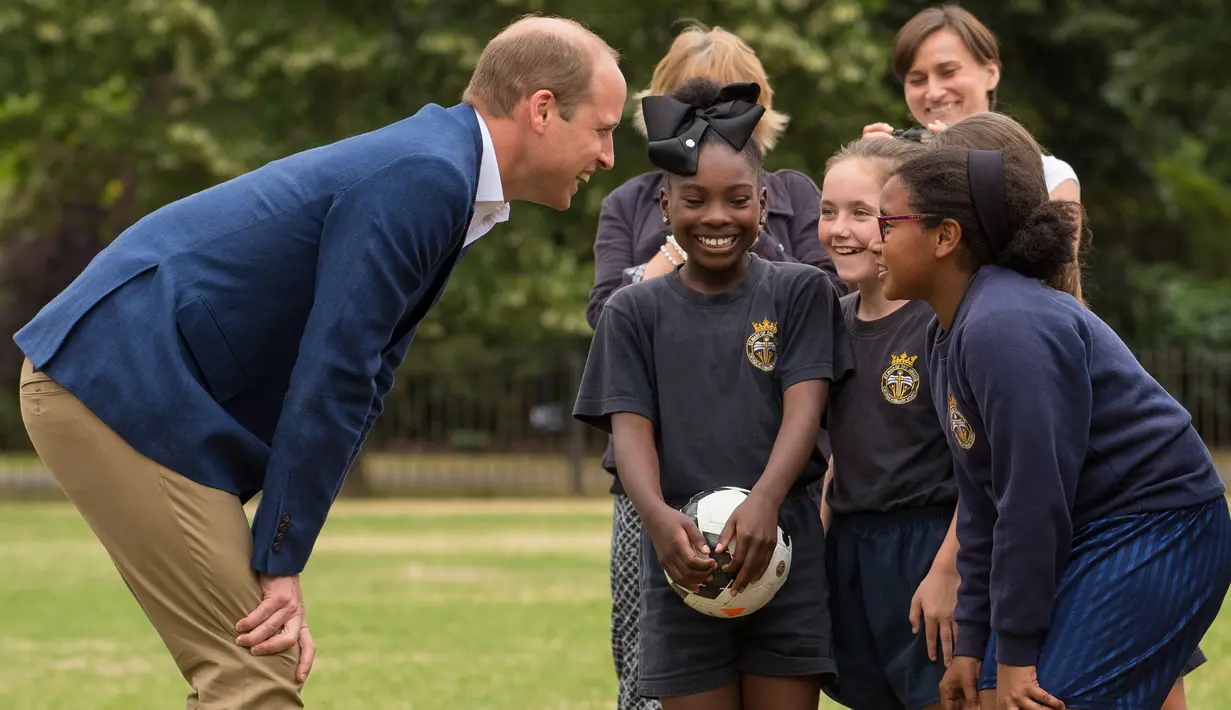 Pangeran William berbincang dengan anak-anak program pendidikan sepak bola Wildcats Girls saat mengunjungi tim sepak bola wanita Inggris, di Kensington Palace, London, Kamis (13/7). (Dominic Lipinski / POOL / AFP)