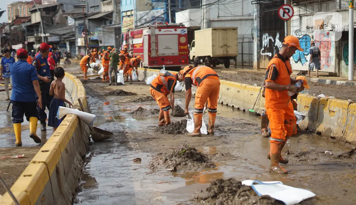 Petugas Penanganan Prasaran dan Sarana Umum (PPSU) membersihkan lumpur yang mengendap di sepanjang Jalan Jatinegara Barat, Kampung Melayu, Jakarta Timur, Kamis (2/1/2020). Petugas melakukan bersih-bersih menyusul mulai surutnya banjir di kawasan tersebut. (Liputan6.com/Immanuel Antonius)