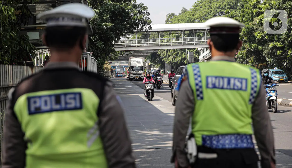Pengendara sepeda motor melintas saat polisi lalu lintas berjaga pada Operasi Zebra Jaya 2022 di Jakarta, Selasa (4/10/2022). Operasi Zebra Jaya dilaksanakan pada tanggal 3 hingga 17 Oktober untuk menekan jumlah pelanggaran lalu lintas. (Liputan6.com/Faizal Fanani)