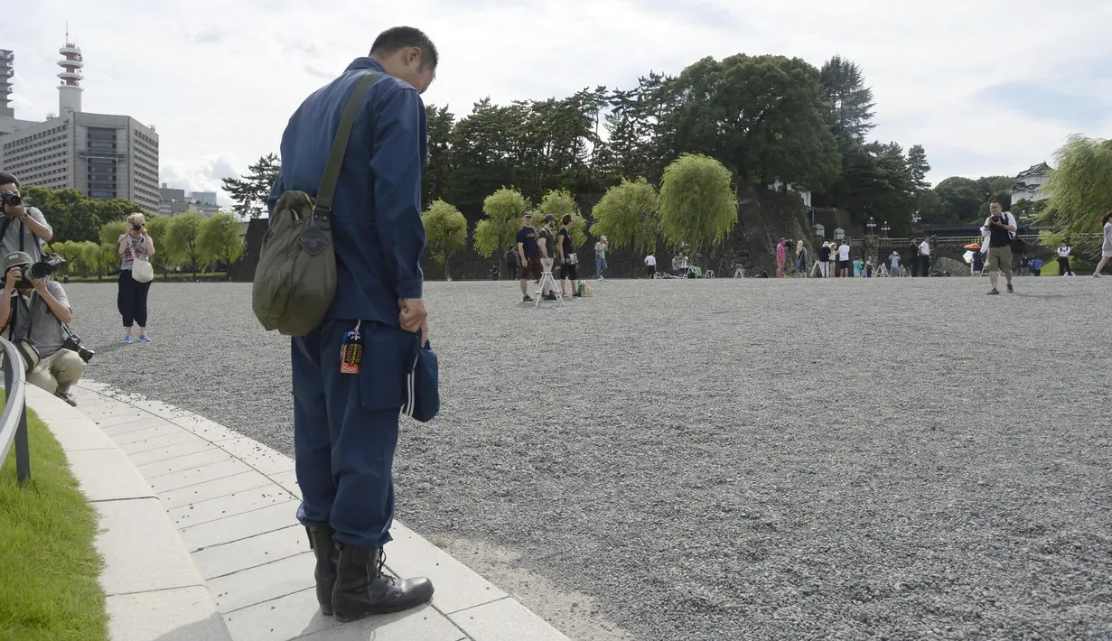 Seorang pria menundukan kepalanya di depan Istana Kekaisaran sambil mendengarkan pesan Kaisar Akihito di Tokyo, Jepang, (8/8). (REUTERS/Kim Kyung-Hoon)