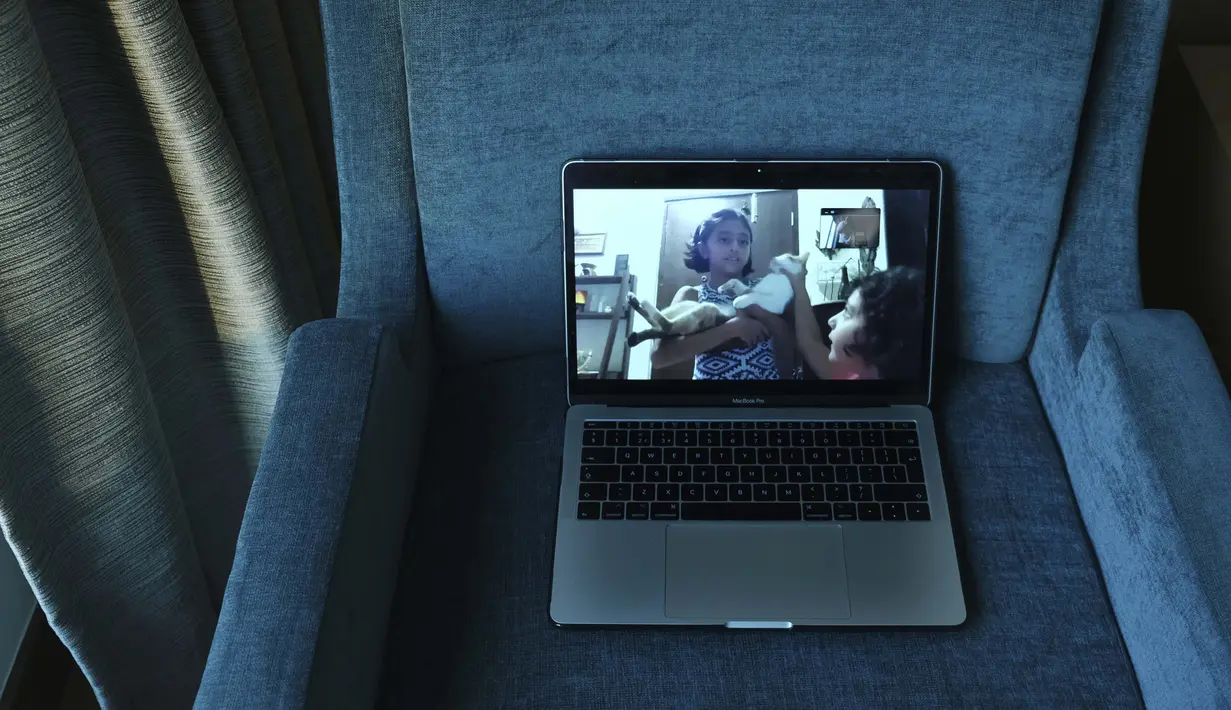 Anak perempuan fotografer Associated Press, Rafiq Maqbool, terlihat pada layar saat video call dengan ayah mereka yang sedang dikarantina di sebuah kamar hotel, Mumbai, India, 24 April 2020. "Jika semua orang disuruh tinggal di rumah, mengapa ayah pergi?" kata putrinya. (AP Photo/Rafiq Maqbool)