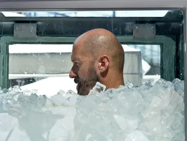 Atlet Austria, Josef Koeberl berupaya memecahkan rekor dengan berendam dalam kotak yang diisi tumpukan es batu di Wina, Sabtu (10/8/2019). Josef Koeberl berhasil memecahkan rekor dunia sebagai pria terlama yang mampu bertahan di dalam es selama 2 jam 8 menit 47 detik. (HERBERT NEUBAUER/APA/AFP)