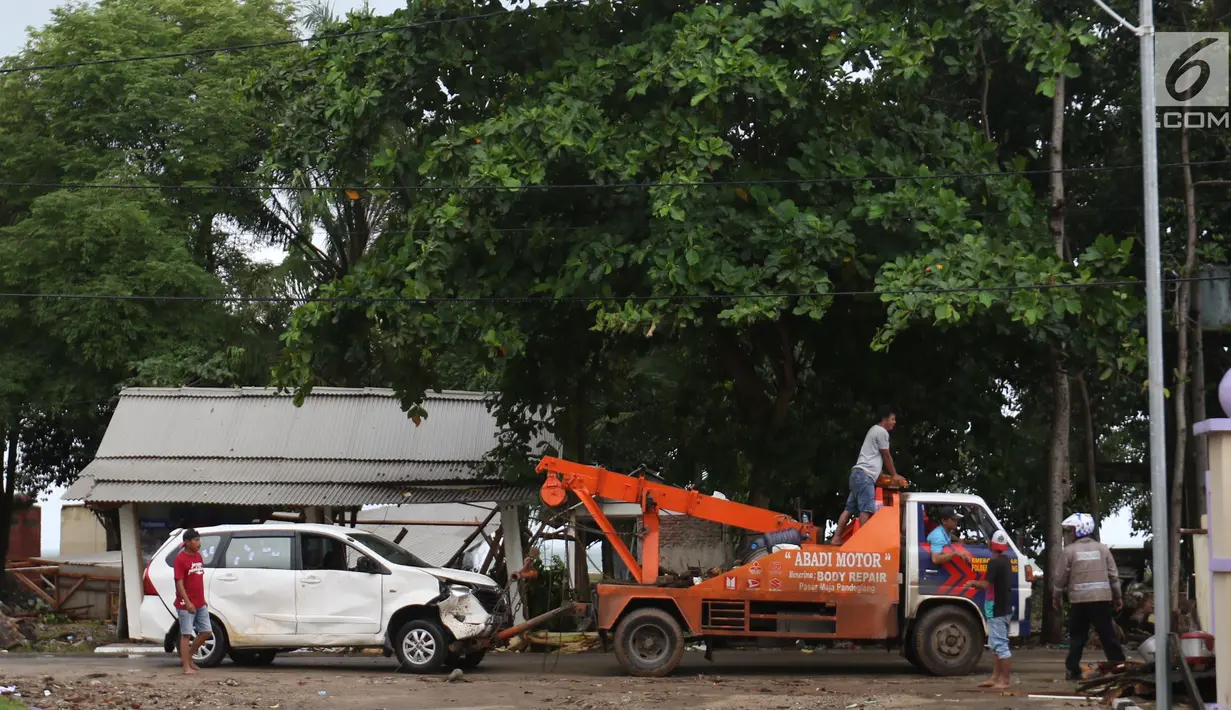 Petugas menderek mobil yang rusak akibat terjangan Tsunami Selat Sunda di Terminal Carita, Banten, Selasa (25/12). Terminal ini dijadikan tempat penampungan mobil yang hancur akibat tsunami. (Liputan6.com/Angga Yuniar)
