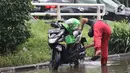 Pengendara memanfaatkan genangan air untuk mencuci kendaraan di Jalan HBR Motik Kemayoran, Jakarta, Selasa (25/2/2020). Hujan yang mengguyur Jakarta sejak Senin (24/2) malam membuat sejumlah kali meluap dan menyebabkan banjir. (Liputan6.com/Helmi Fithriansyah)