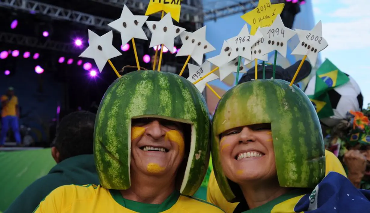 Dua orang suporter Brasil memakai helm yang terbuat dari kulit semangka, Rio de Janeiro, Brasil, Kamis (12/6/2014) (AFP PHOTO/TASSO MARCELO)