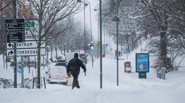 Seorang pria berjalan setelah hujan salju pada tanggal 4 Januari 2024 di Sundbyberg, dekat Stockholm, Swedia. (Jonathan NACKSTRAND/AFP)