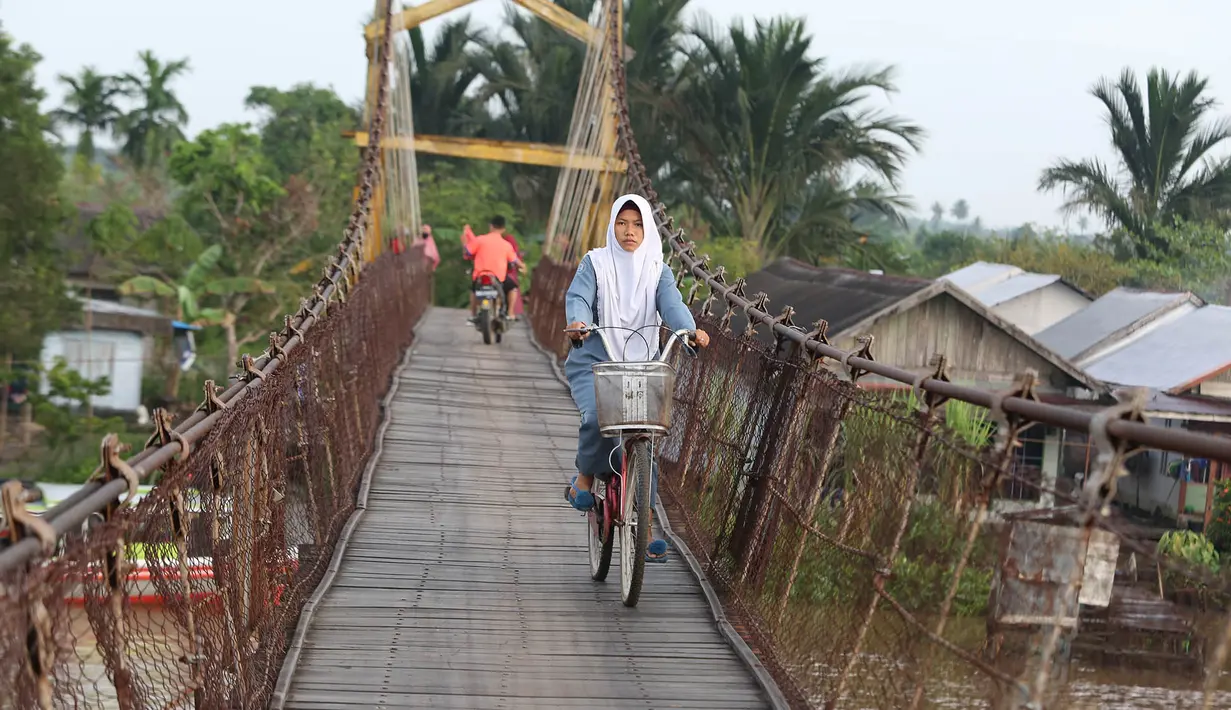 Warga melintasi jembatan penyeberangan di Sungai Martapura, Banjarmasin, Kalimantan Selatan, Selasa (27/3). Selain perahu, jembatan tersebut menjadi satu-satunya akses menyeberang bagi warga sekitar. (Liputan6.com/Immanuel Antonius)