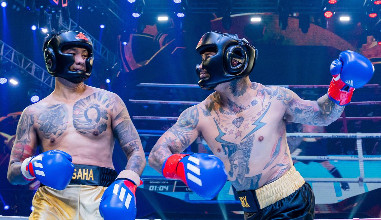 Komika, Uus (kiri), berhasil menghindar dari pukulan pemain drum Superman is Dead, Jerinx, dalam pertandingan tinju Holywings Sport Show (HSS) Series 3 yang berlangsung di Atlas Super Club, Bali, Minggu (10/9/2023). (Dok. Holywings)