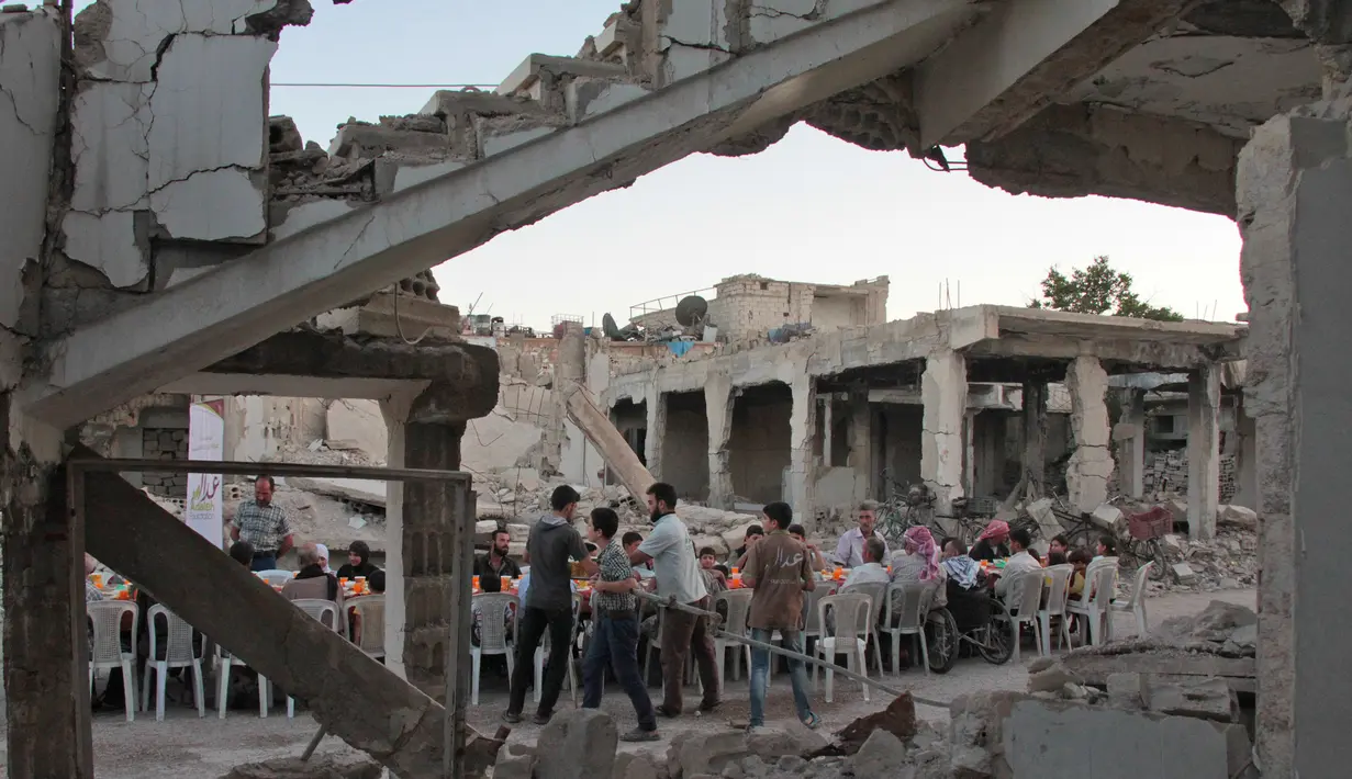 Suasana buka bersama Warga Suriah di tengah reruntuhan bangunan saat bulan suci Ramadan di Kota Douma yang dikuasai pemberontak di pinggiran ibukota Damaskus, Suriah, (18/6). (AFP Photo/Hamza Al-Ajweh)