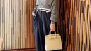 Ia juga tampil stylish dengan atasan knit abu-abu yang memerlihatkan keindahan pundaknya dipadukan celana navy. Dan menengteng tas Hermes putih gadingnya. credit: Instagram/(@chelseaoliviaa)
