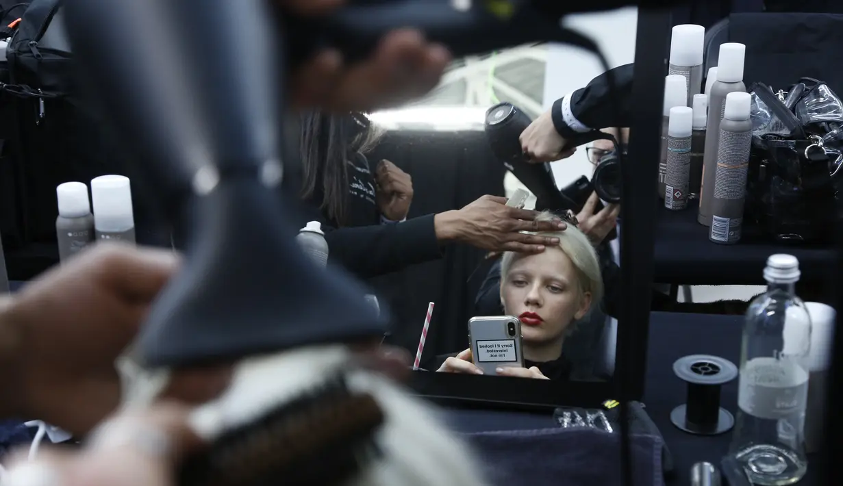 Model saat dirias di belakang panggung sebelum memamerkan koleksi busana wanita Fall Winter 2020 Jil Sander selama Fashion Week di Milan, Italia, Rabu, (19/2/2020). (AP Photo/Domenico Stinellis)