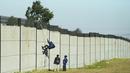 Seorang kolektor besi tua memanjat tembok untuk mencari besi tua untuk didaur ulang di pabrik pengolahan logam di Germiston, timur Johannesburg, Afrika Selatan (30/5/2022). Pengumpul besi tua di area tersebut melompat ke dinding beton untuk mengumpulkan besi tua dan kemudian menjualnya ke toko bekas. (AP Photo/Themba Hadebe)