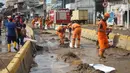 Petugas Penanganan Prasaran dan Sarana Umum (PPSU) membersihkan lumpur yang mengendap di sepanjang Jalan Jatinegara Barat, Kampung Melayu, Jakarta Timur, Kamis (2/1/2020). Petugas melakukan bersih-bersih menyusul mulai surutnya banjir di kawasan tersebut. (Liputan6.com/Immanuel Antonius)